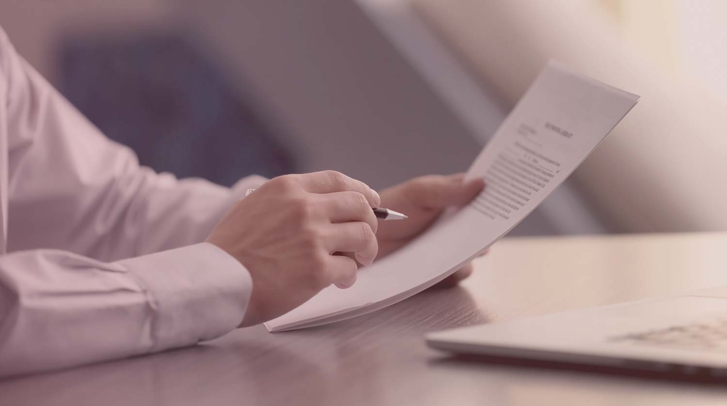Hands holding a resume at an offic desk.