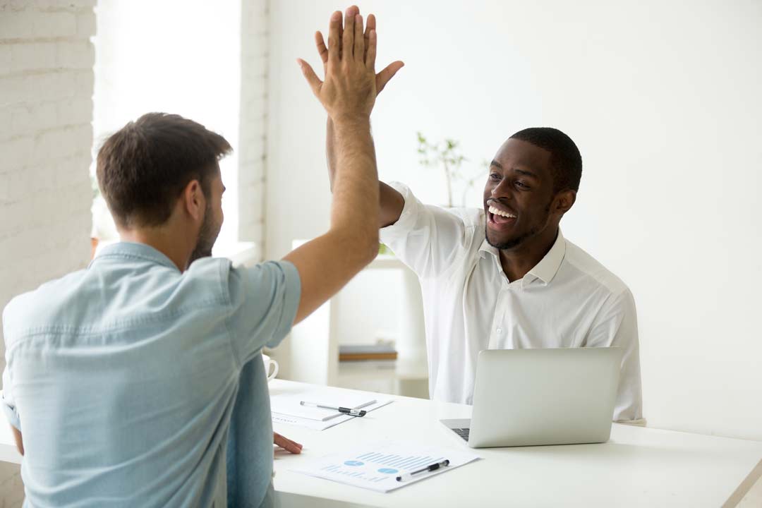 Two coworkers sharing a high five after deciding what to do with their CV picture.